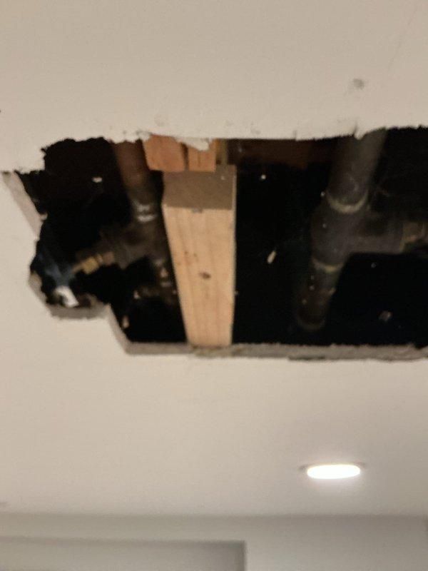 Located and inspected water leak in garage ceiling that had begun during the weekend. Upon investigation, accessed the affected area by creating a ceiling cutout, revealing copper water supply lines with visible corrosion and a deteriorated brass shutoff valve. Identified this as the source of the leak.