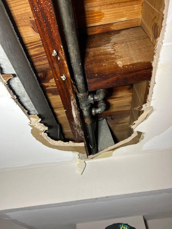 Responded to emergency call for frozen/burst pipe. Removed damaged drywall sections to access affected plumbing in ceiling. Identified water damage to surrounding wooden joists and possible mold growth on structural components. Repaired compromised pipe and fittings to restore water service.