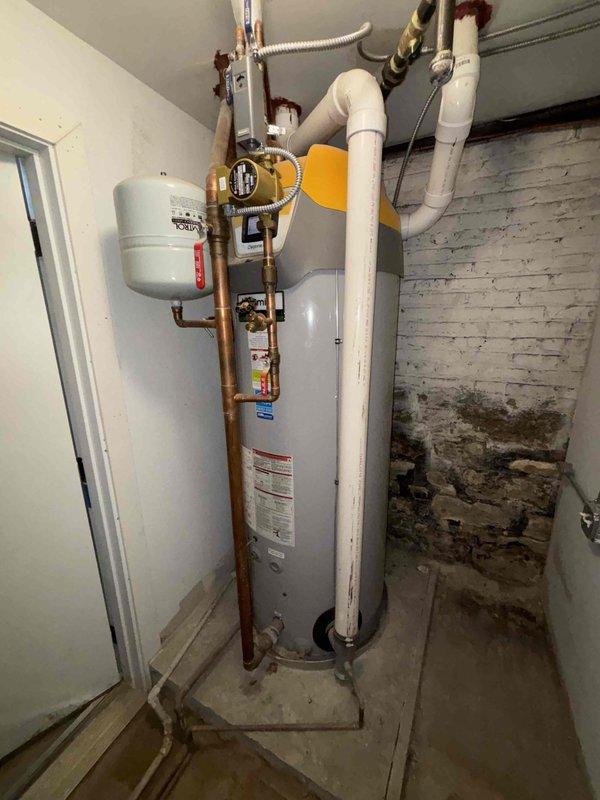 Cleared severe clog from bathroom drain that was causing slow drainage. Inspected water heater system in basement utility area, noting copper supply lines, expansion tank, and drain piping configuration. Provided verbal recommendations for water heater maintenance and exterior cleanout rodding services.