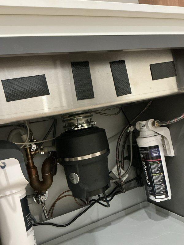 Responded to a kitchen sink overflow issue. Inspected under-sink components including garbage disposal unit, copper plumbing, and filtration system. Serviced brass shutoff valve and elbow fitting that were causing the clog, restoring proper drainage function.