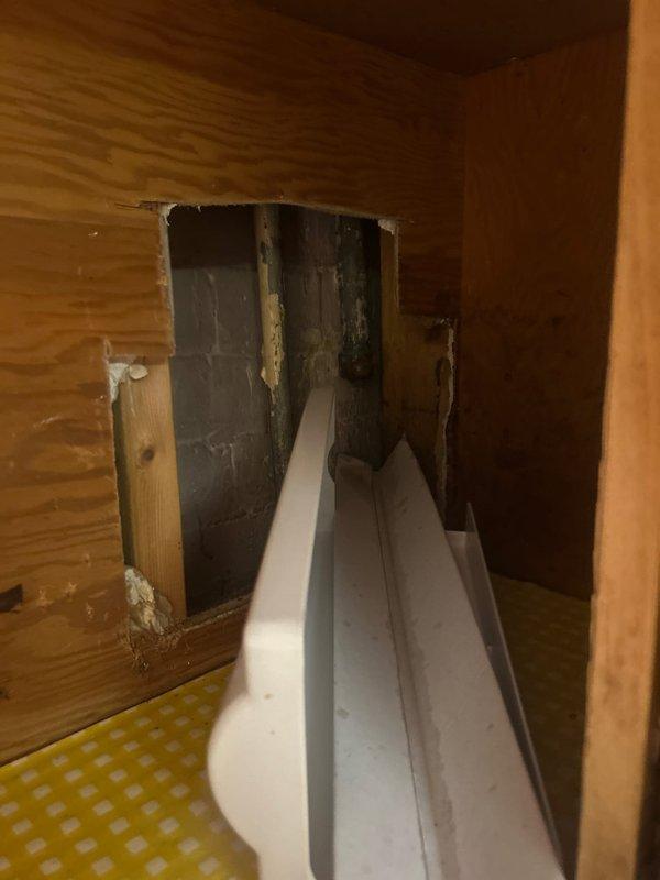 Located and identified water leak source in basement, originating from a corroded metal pipe with deteriorating elbow joint. Accessed the affected area by creating an inspection opening in the wall structure, revealing aged plumbing components with visible wear and discoloration requiring attention.