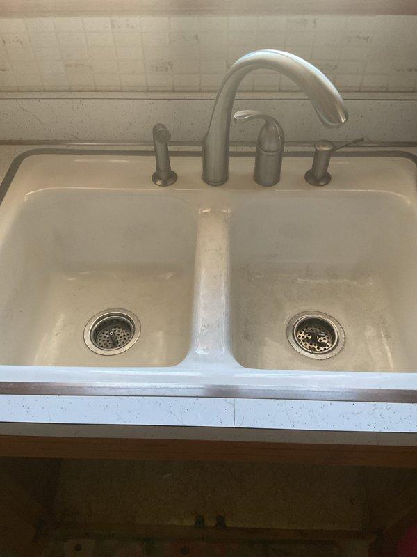 Responded to service call for kitchen double-basin sink with slow drainage. Visual inspection revealed standard P-trap configuration with horizontal connection pipe between drains. Successfully cleared clog and restored normal drainage function in both basins.