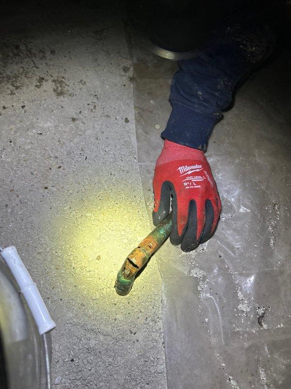 Responded to customer request for water leak investigation in a confined crawl space. Upon inspection, identified a heavily corroded copper pipe fitting with active leak. Observed significant corrosion damage, moisture accumulation on concrete surface, and deteriorated insulation in the surrounding area.