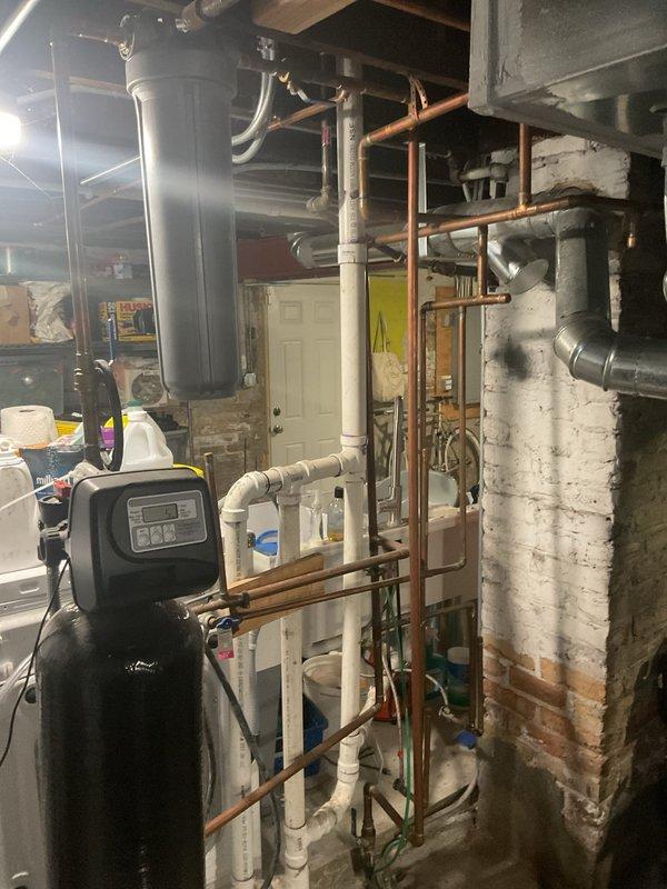 Conducted assessment of customer's lead service line requiring replacement. Inspected basement utility area containing water softener/filtration system with PVC and copper piping network. Also evaluated sewer line replacement needs as requested by customer. Photos documented existing plumbing configuration, including supply lines and drainage system in the basement mechanical room.