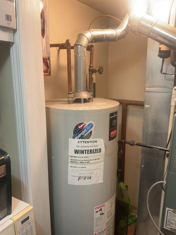 Responded to dispatch call for tanked water heater service. Inspected existing water heater system which was winterized as indicated by attached notice. Observed proper ventilation and connection components including copper piping. Noted protective bubble wrap on vertical copper pipes in utility area, suggesting recent installation or ongoing work.