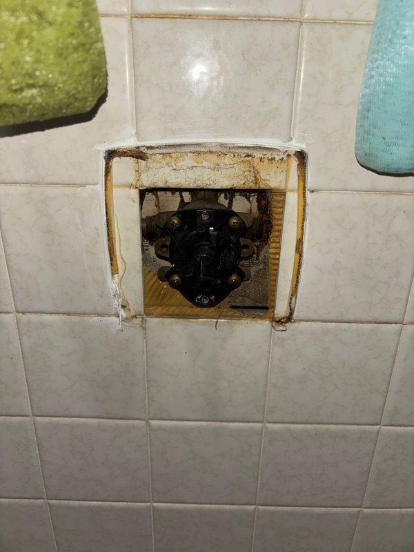Completed replacement of damaged recessed valve assembly in bathroom tile wall which showed significant water damage and deterioration. Additionally, replaced malfunctioning bathroom exhaust fan that exhibited extensive mold growth and moisture damage around housing, improving ventilation and addressing potential moisture issues.