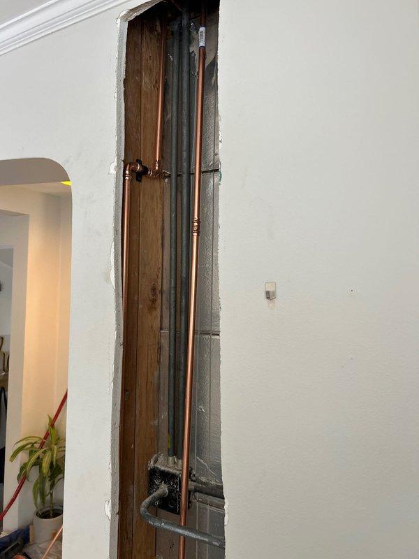 Accessed plumbing system by opening drywall section to expose copper water lines and PVC pipes within the wall cavity. Performed necessary repairs on the exposed plumbing infrastructure as sold by Jon, then documented the repair area with detailed photos showing both the exposed piping system and surrounding wall structure.