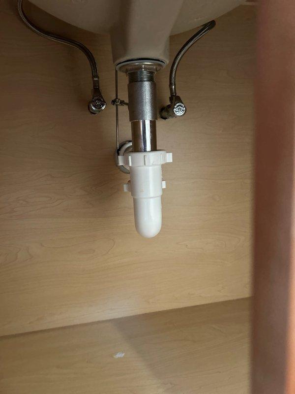 Responded to service call for bathroom sink leaking from underneath into vanity storage area. Upon inspection, found faulty drain assembly connection. Replaced P-trap assembly, tightened all connections, and verified proper water flow with no leaks. System now functioning normally.