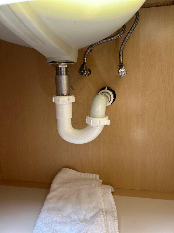 Responded to service call for bathroom sink leaking from underneath into vanity storage area. Upon inspection, found faulty drain assembly connection. Replaced P-trap assembly, tightened all connections, and verified proper water flow with no leaks. System now functioning normally.