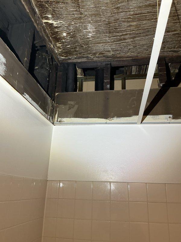 Conducted on-site assessment for customer's request to install a new bathroom in existing building. Inspection revealed significant ceiling damage with exposed wooden joists and deteriorated substrate material, likely indicating previous water damage or aging infrastructure. Bathroom currently has partial tile walls and requires complete renovation before new plumbing installation can proceed.