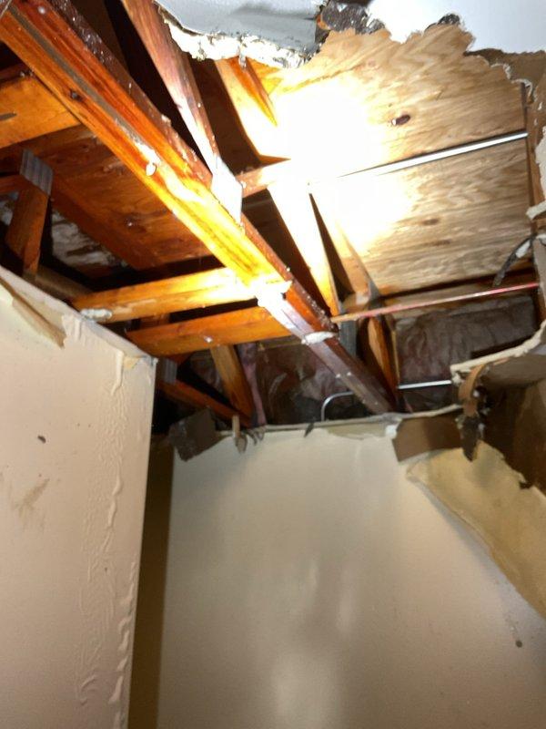Responded to emergency call for a burst pipe that caused significant ceiling damage. Upon inspection, discovered water had leaked through the ceiling, creating a large hole and exposing structural joists. Repaired the burst pipe and installed a new Richmond water heater (12-year Self-Cleaning model) with proper copper line connections, venting, and valves to prevent future issues.