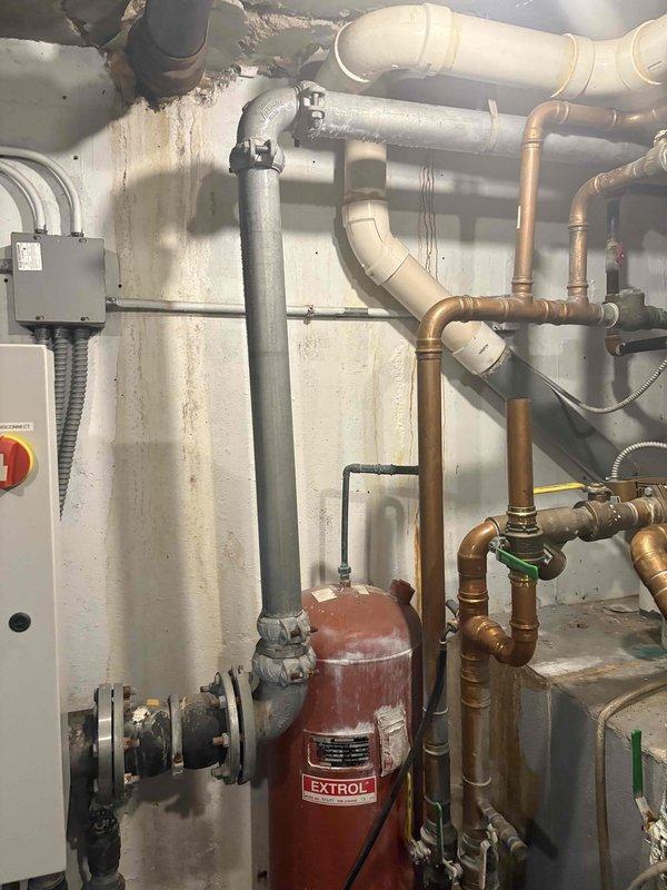 Completed service call back to inspect plumbing infrastructure in utility area. Examined copper and PVC piping system including P-trap configuration, checking connections between different pipe materials for proper sealing. Inspected expansion tank (EXTROL) and associated valves, noting minor water staining on adjacent wall that will require monitoring.