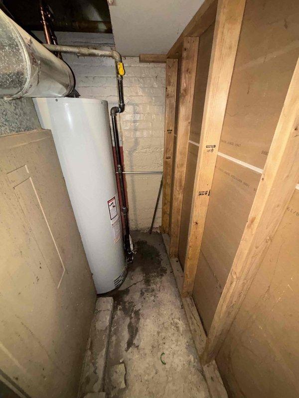 Completed installation of a 40-gallon atmospheric water heater in a confined basement utility area. Removed old unit showing signs of leakage, installed new heater with proper copper pipe connections, and ensured proper venting through existing galvanized ductwork. Installation required specialized positioning due to extremely tight space constraints.