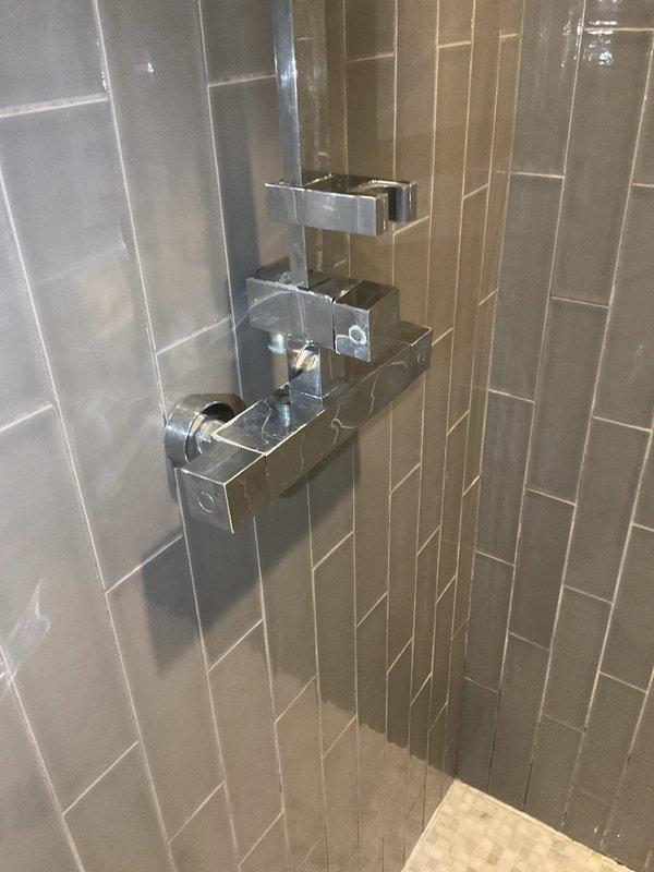 Responded to a service call for a leaky showerhead in a residential bathroom. Upon inspection, found a PORCELANOSA shower fixture showing signs of water leakage. Repaired the faulty valve, tightened all connections, and verified proper operation with no further leakage.