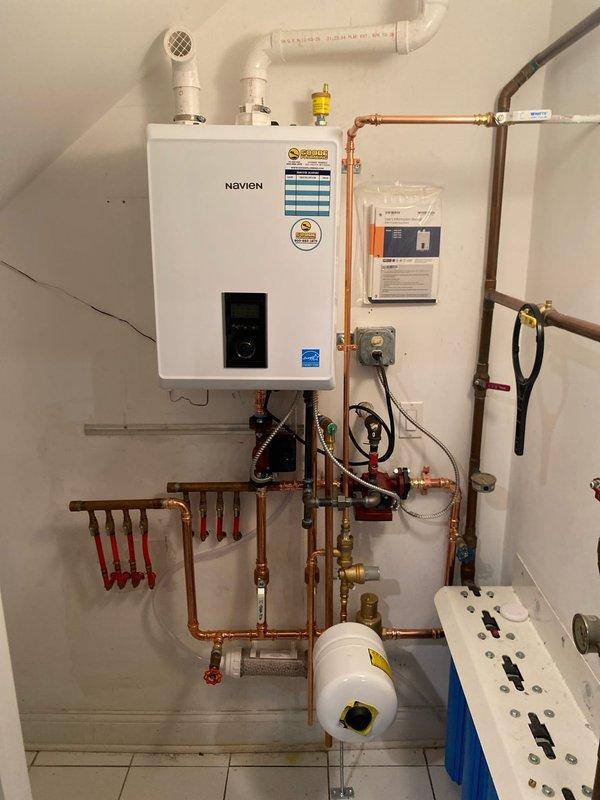 Successfully installed a new Navien tankless water heater system after the client's previous boiler was condemned. Work included comprehensive copper pipe installation with multiple valves and connectors, integration of a red circulator pump, and proper connection of PVC vent pipes for exhaust and intake. System was completed with installation of an expansion tank and water filtration components, all professionally mounted and tested for optimal performance.