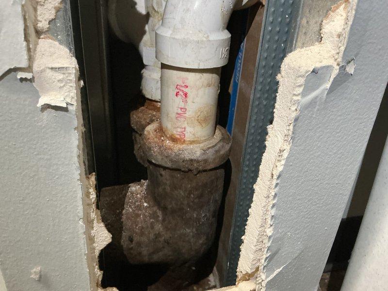 Conducted site visit for customer who requested evaluation of a suspected seal issue between washing machine and main stack. Inspection revealed deteriorated connection at the PVC to cast iron transition, showing significant corrosion and mineral deposits. Multiple wall sections had been previously opened with temporary patches visible. Documented condition of plumbing system and identified need for proper pipe transition repair to prevent further water damage.