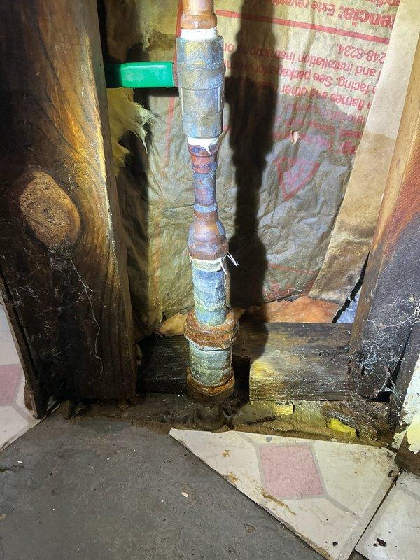 Responded to callback for Jon. Inspected basement utility space with visible water staining on concrete floor. Examined copper supply line showing significant corrosion and oxidation at joints with greenish-blue patina formation. Identified potential leakage at connection points and signs of water damage on surrounding wooden framing.