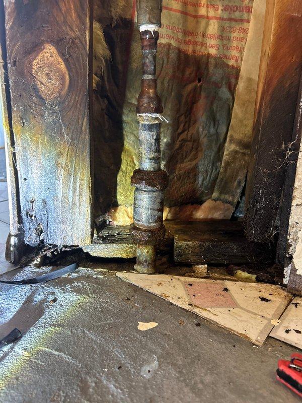 Responded to emergency water leak call involving corroded galvanized pipe in basement. Shut off main water supply at valve, then removed damaged section of wall to access deteriorated plumbing infrastructure. Replaced severely corroded vertical pipe section and fittings with new copper piping, installed proper shutoff valve, and verified system integrity with pressure test. No additional leaks detected after restoration of water service.