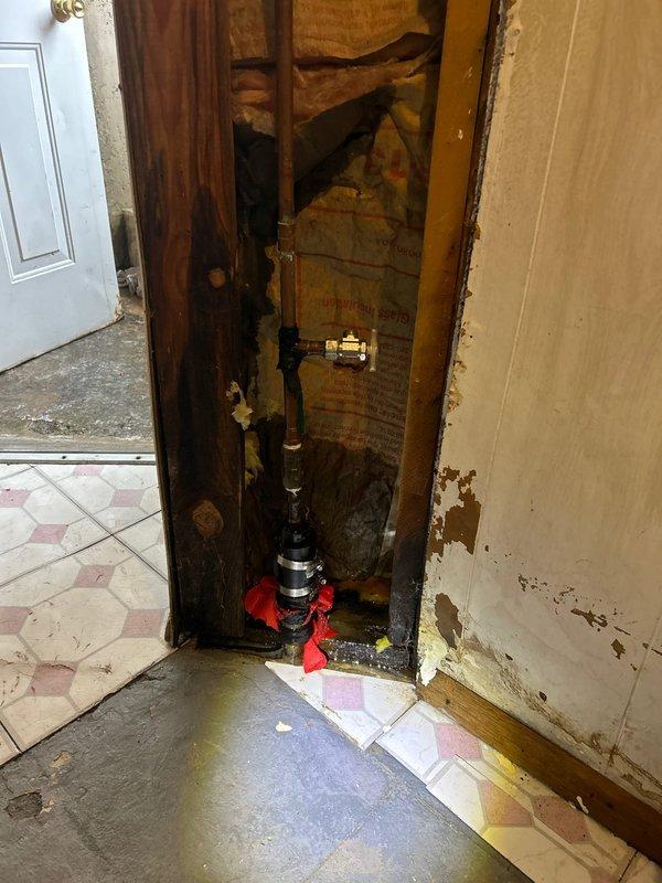 Responded to emergency water leak call involving corroded galvanized pipe in basement. Shut off main water supply at valve, then removed damaged section of wall to access deteriorated plumbing infrastructure. Replaced severely corroded vertical pipe section and fittings with new copper piping, installed proper shutoff valve, and verified system integrity with pressure test. No additional leaks detected after restoration of water service.