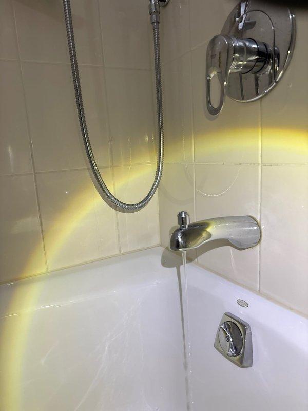 Responded to a rescheduled service call for a leaking bathtub faucet. Upon inspection, removed the shower valve trim to access the internal components, revealing the valve cartridge and water inlet connections requiring service. Successfully repaired the ongoing leak issue.