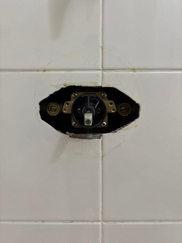 Responded to a rescheduled service call for a leaking bathtub faucet. Upon inspection, removed the shower valve trim to access the internal components, revealing the valve cartridge and water inlet connections requiring service. Successfully repaired the ongoing leak issue.