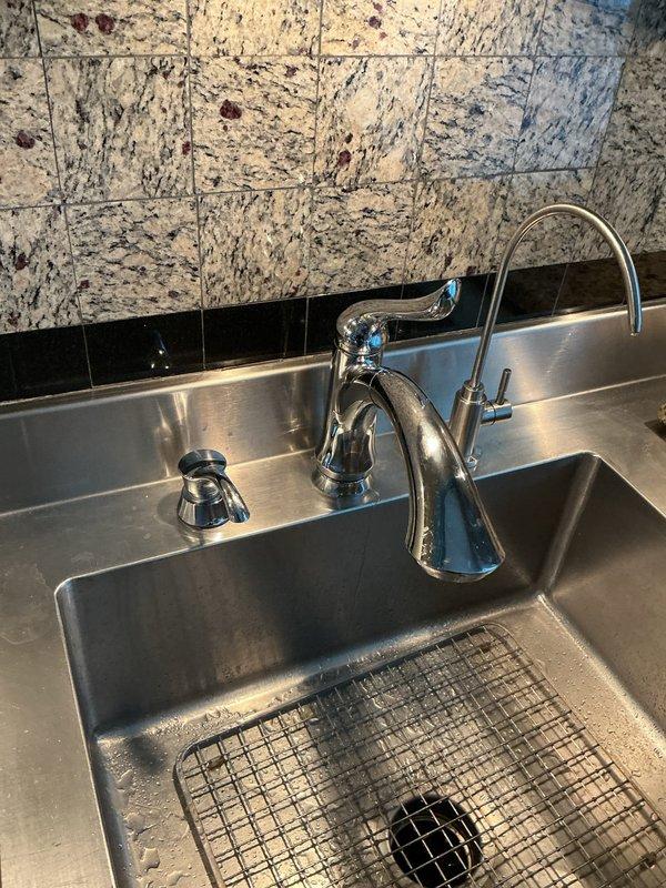 Responded to emergency service call for leaking faucet in kitchen. Upon inspection, found a modern chrome high-arch faucet with water leakage. Disassembled faucet assembly, replaced worn cartridge and gaskets, and verified proper operation of both main faucet and auxiliary dispenser. Also inspected 1/4 HP garbage disposal unit and surrounding plumbing connections to ensure no additional leaks were present in the system.