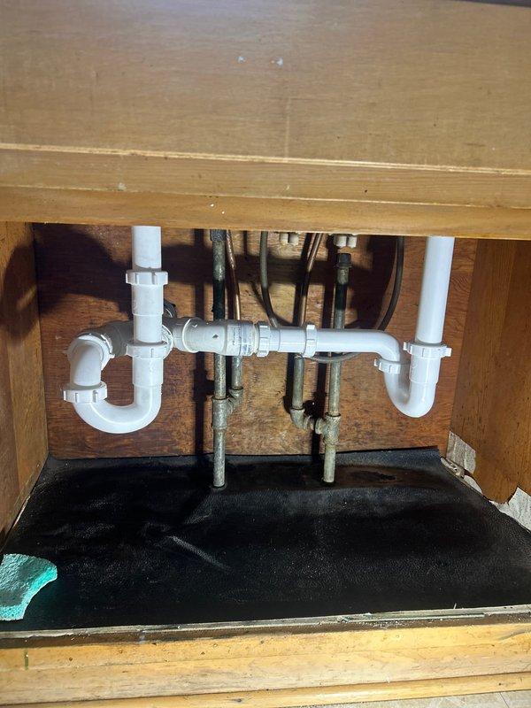 Replaced severely corroded metal P-trap assembly showing significant black mold and water damage with new PVC drain assembly. Installed complete P-trap configuration with proper threaded connections to address persistent sink clog and eliminate leakage that had caused cabinet base deterioration.