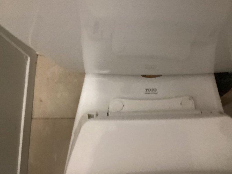 Responded to service call for malfunctioning toilet. Inspected TOTO toilet and internal tank components, noting mineral buildup and staining on the fill valve assembly. Serviced the toilet mechanism, focusing on the red float valve component and associated plumbing to restore proper functionality.