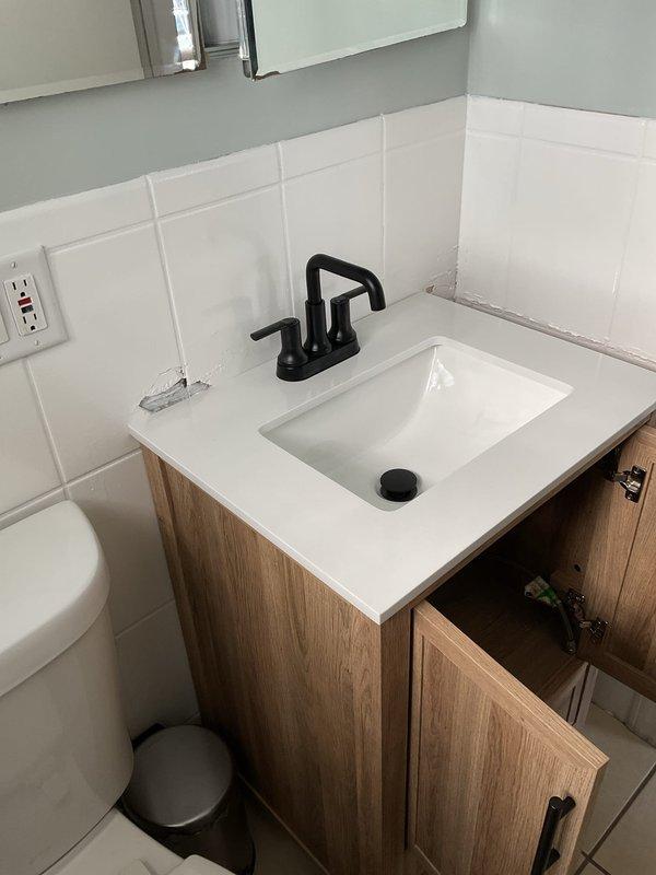 Completed installation of customer-supplied bathroom vanity including properly anchoring cabinet to wall and connecting sink drain assembly. Inspected existing drain line for blockages and ensured proper drainage. Sealed gap between vanity countertop and tile backsplash with appropriate waterproof caulking to prevent water intrusion.