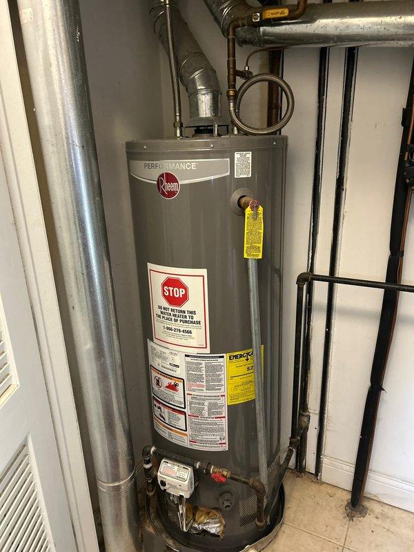 Investigated reported washing machine leak from upper unit affecting customer's residence. Inspected the Rheem Performance water heater system and surrounding plumbing connections. Identified and documented potential leak sources in the mechanical equipment installation, particularly noting moisture indicators around the exhaust vent connection point and insulation material.