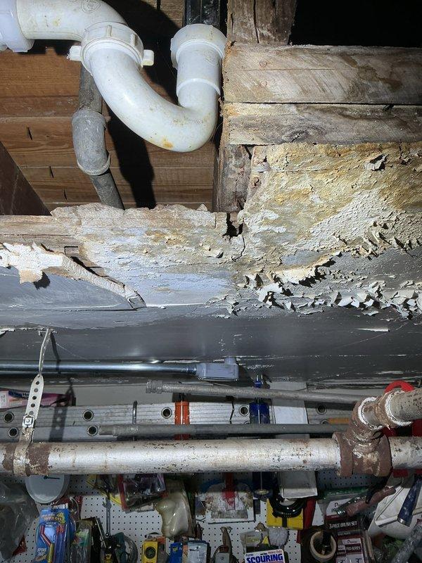 Responded to service call transferred from Brian to Jon. Inspected residential plumbing system where significant wood deterioration and water damage was observed around the PVC drainage system with P-trap configuration. Documented condition of Bradford White water heater installation and associated piping infrastructure including copper supply lines, metal exhaust venting, and pressure gauge components.