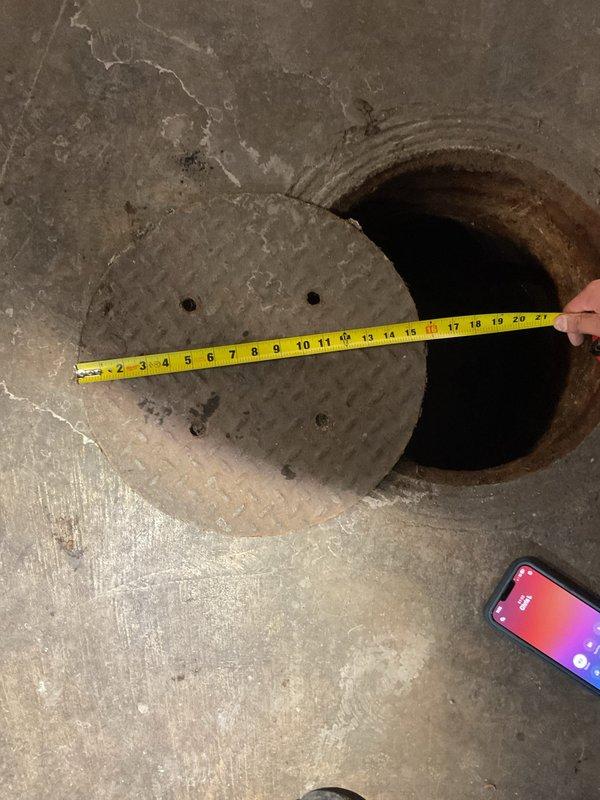 Conducted on-site assessment of damaged sewer cover in basement utility area. Measured existing circular access cover (approximately 17-18 inches in diameter) that showed significant deterioration and cracking. Documented surrounding concrete floor condition, which exhibited multiple settlement cracks and moisture issues at the wall junction. Provided customer with estimate for replacement cover as requested.