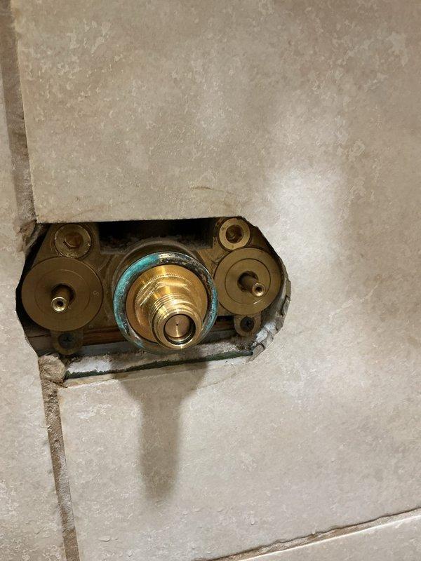 Responded to emergency call for a slow leak in shower isolation valve. Upon inspection, found brass valve assembly showing signs of corrosion with greenish patina developing around outer edges. Accessed valve through wall opening, documented condition with photos, and determined building water shutdown required for complete repair. Scheduled return visit for full valve replacement during planned building shutdown on 2/10/26.