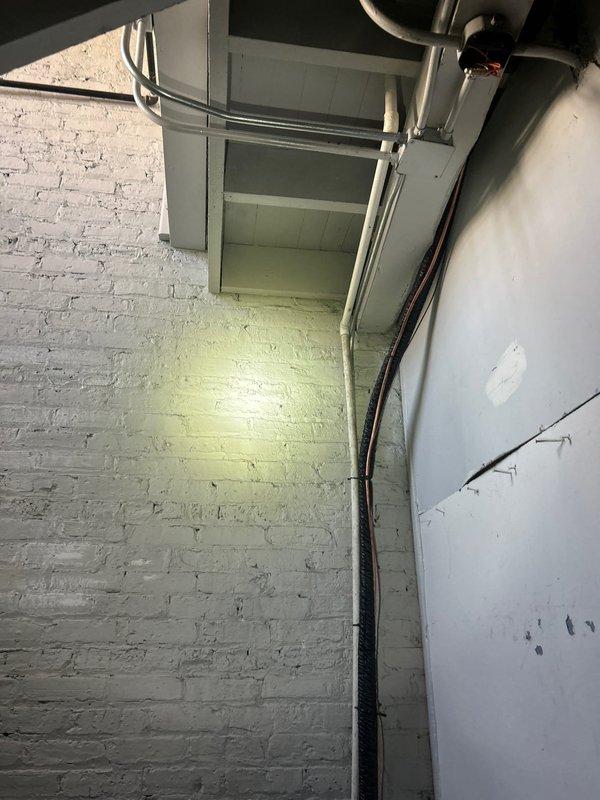 Inspected second-floor water heater with damaged drain line that froze and now discharges into a tenant-maintained bucket. Evaluated HVAC utility area and surrounding plumbing infrastructure to determine optimal repair solution for the compromised condensate drainage system.