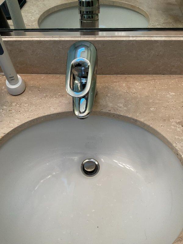 Responded to service call for a leaking bathroom faucet with automatic sensor. Upon inspection, discovered water actively leaking from the P-trap connection, requiring installation of a new P-trap assembly and tightening of all connection points. Tested system thoroughly after repair, confirming complete resolution of leak with no additional issues detected.