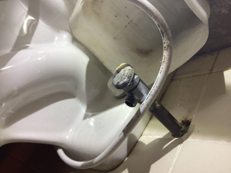Responded to customer complaint of toilet leaking from wall for approximately 2 weeks. Inspection revealed aging water supply line with visible corrosion and mineral deposits at connection points. Replaced deteriorated metal braided supply line and tightened valve fitting to eliminate leak. Checked floor area for water damage and verified proper operation after repair.