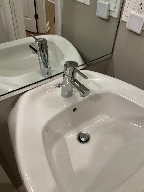 Successfully installed a new contemporary chrome faucet with cylindrical handle design on a white porcelain bathroom sink. Completed full installation with proper sealing and connection to existing plumbing. Final inspection confirmed proper water flow and no leaks.