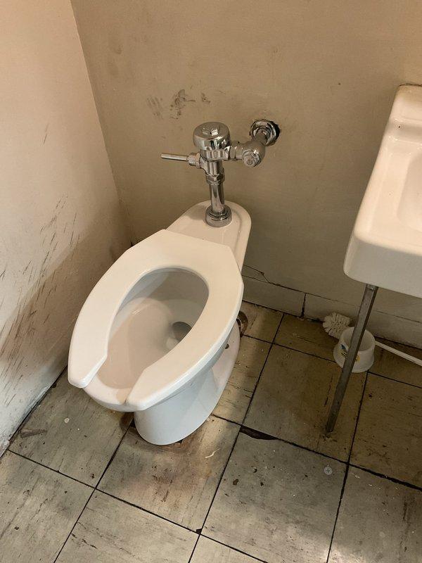 Completed replacement of severely corroded floor drain in commercial bathroom facility. Removed existing rusted fixture and installed new drain assembly with proper sealing to prevent water damage. Also inspected toilet with chrome flush valve and adjacent wall-mounted sink for potential related issues.