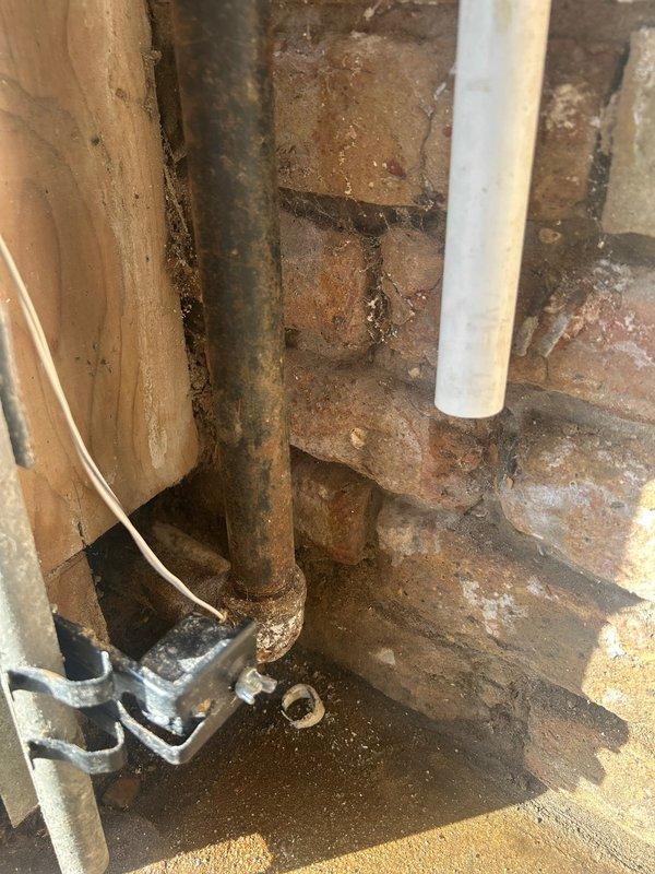Conducted comprehensive assessment of existing plumbing infrastructure, including inspection of corroded metal supply pipes and gas meter installation against brick wall. Documented condition of vertical rusty pipe system, PVC connections, and gas meter configuration with associated piping. Photos taken to document current state for estimate purposes.