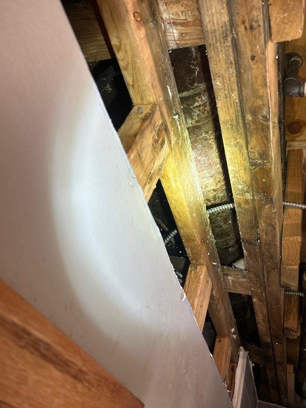 Conducted site assessment of exposed ceiling/wall framework to prepare drain repipe quote. Documented existing plumbing infrastructure including PVC piping and metal conduits running through aged wooden joists. Meeting scheduled with client to discuss comprehensive repipe proposal.