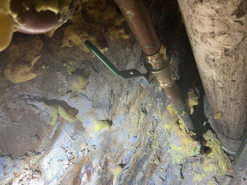 Located and identified source of high water consumption in 3-flat apartment building. Inspection revealed corroded copper pipe with significant oxidation and a compromised connection point. Found evidence of moisture intrusion and previous repair attempts using spray foam insulation around the plumbing components.