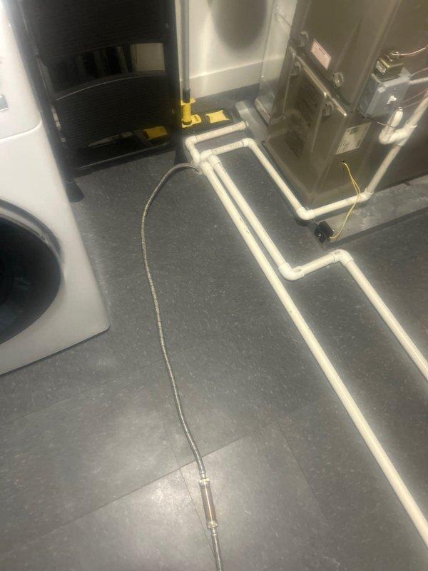 Responded to customer report of ceiling leak originating from bathroom/laundry room above. Conducted visual inspection of the area, identifying junction points between walls where moisture intrusion was occurring. Examined utility room plumbing configuration, focusing on L-shaped pipe arrangement and connections to mechanical systems. Located and documented the source of the water leak for future repair.