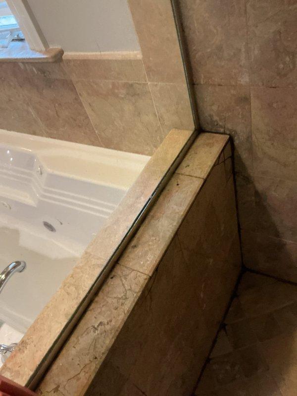 Responded to a water leak affecting a downstairs unit. Upon inspection, identified water seepage from the bathtub surround area where deteriorated grout and caulking had failed at the tub-to-wall junction. Removed compromised sealing materials, thoroughly dried affected areas, and applied new silicone caulking to create proper waterproof barrier around tub perimeter and along floor junction to prevent further water intrusion.