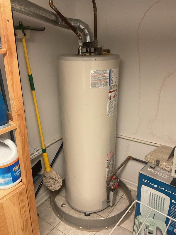 Assessed client's request to replace existing GE 50-gallon natural gas water heater (model PG50T9A) and install water softening/filtration systems. Inspected current installation, noting copper pipe configuration and existing water heater placement in utility room with proper drain pan. Provided recommendations for comparable replacement unit along with compatible water softening system and under-sink filtration options for the kitchen.