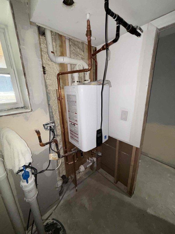 Successfully uninstalled a wall-mounted tankless water heater from a partially finished utility area, disconnecting all copper supply lines and PVC drainage components. Also removed toilet fixture as requested by customer, ensuring proper capping of water lines and waste connections.