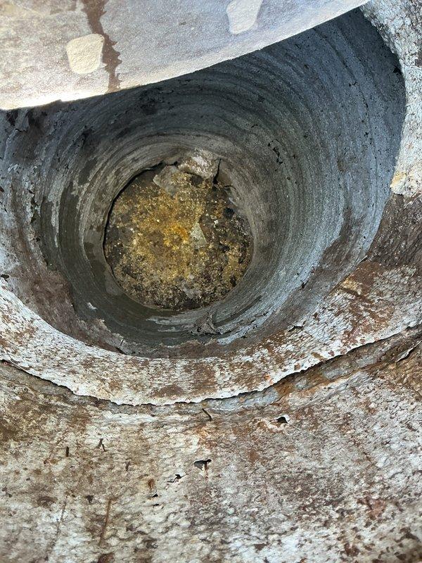 Performed hydro-flush service on actively backed up commercial drain system. Cleared blockage allowing proper drainage into city main. Inspected concrete pipe structure showing significant mineral deposits and deterioration, documented condition with photos of pipe interior and exterior meter access point.