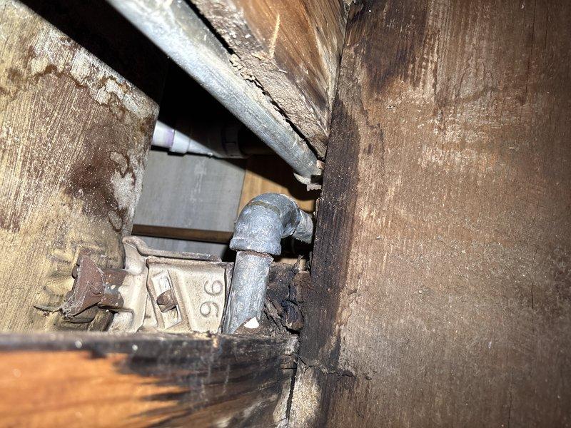 Responded to early morning service call to address deteriorated plumbing system. Upon inspection, discovered aged galvanized pipe fittings with visible corrosion and surrounding water-damaged wooden structure. Completed replacement of compromised galvanized elbow joint and associated piping components to prevent further structural deterioration.
