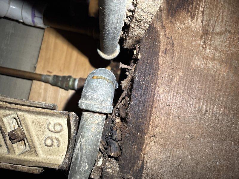 Responded to early morning service call to address deteriorated plumbing system. Upon inspection, discovered aged galvanized pipe fittings with visible corrosion and surrounding water-damaged wooden structure. Completed replacement of compromised galvanized elbow joint and associated piping components to prevent further structural deterioration.