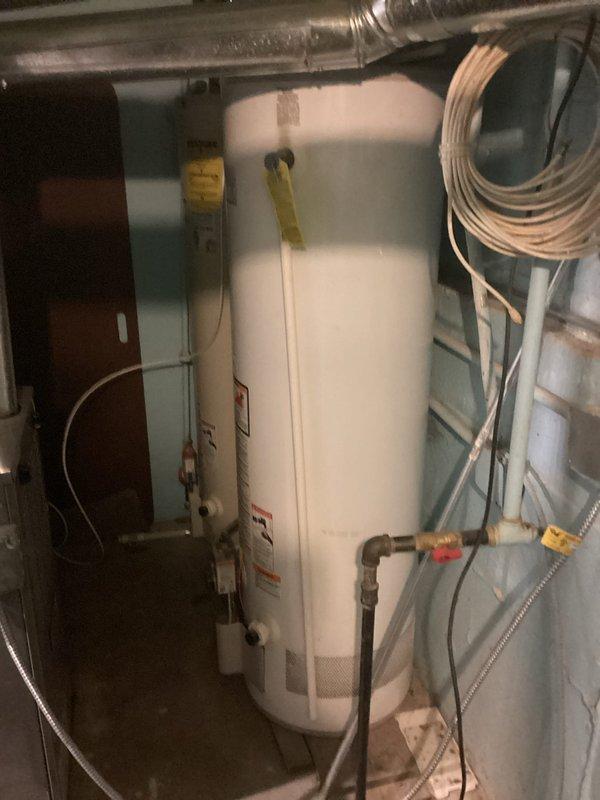 Inspected water heater installation with plastic discharge pipes that require replacement with metal piping per code requirements. Observed current setup includes PVC discharge piping connected to T&P valve, which presents a safety concern due to potential failure under high temperature conditions. Recommended replacement with proper copper or galvanized steel discharge piping to ensure code compliance and system safety.