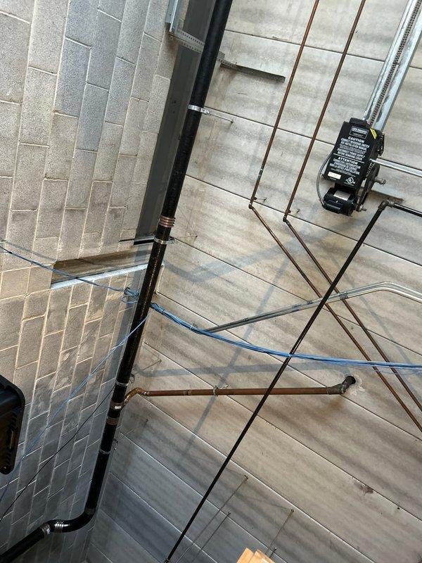 Conducted initial assessment of commercial plumbing system, documenting copper pipe network and control junction box installation in utility area. Identified and photographed vertical black pipe with 90-degree bend near ceiling in concrete block wall section. Second service call scheduled for 2/10/26 to complete necessary repairs.
